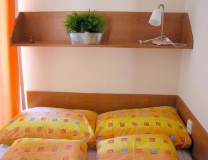 a bed with two pillows and a plant on a shelf at Apartmán Oščadnica in Oščadnica