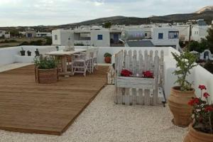 a patio with a table and chairs and buildings at Pebbles Villa with private roof garden in Aliki