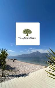 un cartel en una playa con un árbol. en Villa CorteOlivo Rooms, en Torri del Benaco