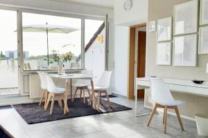 une salle à manger avec une table et des chaises blanches dans l'établissement Modernes und ruhiges Appartement mit Loggia, à Marl