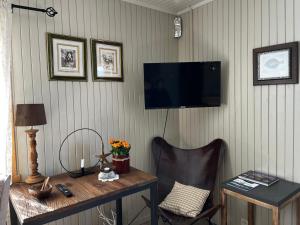 Habitación con escritorio y TV en la pared. en Olenilsøy Cabins, en Reine