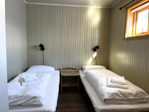 two twin beds in a room with a window at Olenilsøy Cabins in Reine