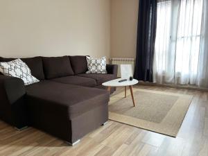 ein Wohnzimmer mit einem braunen Sofa und einem Tisch in der Unterkunft Lubata 5 Apartments - 2 bedrooms in Sofia