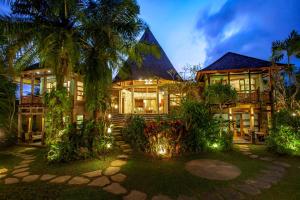 a house with palm trees and lights in front of it at Aryaswara Villa Ubud in Ubud