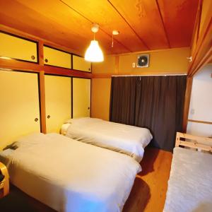 mooi guesthouse 日新町 في أيزواكاماتسو: غرفه فيها ثلاث اسره فيها مصباح