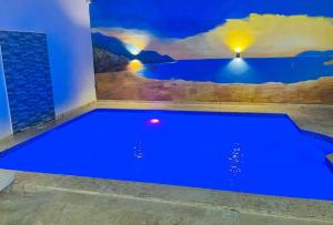 una piscina blu in una stanza con un dipinto sul muro di Complejo girasol a Santo Domingo