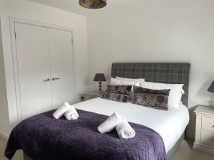 ein Schlafzimmer mit einem Bett mit Handtüchern auf einer lila Decke in der Unterkunft Millwood in Aviemore