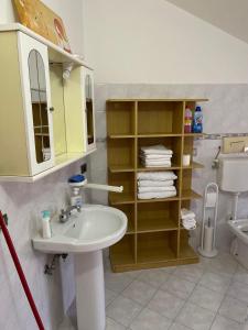 a bathroom with a sink and a shelf with towels at Il Bacio del Mare in Agropoli +21 photos