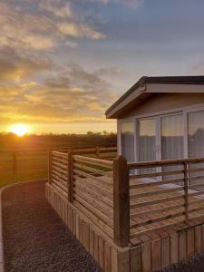 a house with a fence and a sunset in the background at Drumrammer Farm Lodge in Ahoghill