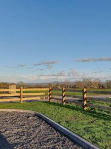a fence on a dirt road next to a field at Drumrammer Farm Lodge in Ahoghill