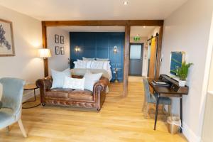 West Highland Hotel في ماليغ: غرفة نوم مع أريكة وسرير ومكتب