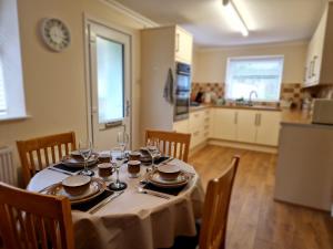 - une table avec des assiettes et des verres dans la cuisine dans l'établissement Lewis Gethin House, Newly renovated cottage sleeps 9, close to bike park wales, à Merthyr Tydfil