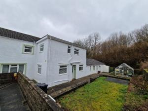 ein weißes Haus mit einem Garten davor in der Unterkunft Lewis Gethin House, Newly renovated cottage sleeps 9, close to bike park wales in Merthyr Tydfil