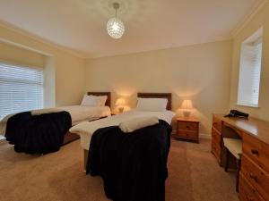 ein Schlafzimmer mit zwei Betten und einem Schreibtisch und zwei Lampen in der Unterkunft Lewis Gethin House, Newly renovated cottage sleeps 9, close to bike park wales in Merthyr Tydfil