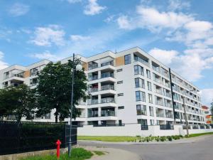 Biały apartamentowiec z czerwonym hydrantem przeciwpożarowym w obiekcie Apartament Złota Brama w mieście Ełk