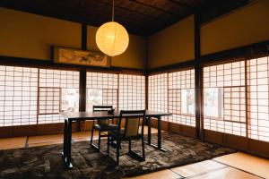 ein Raum mit Tisch und Stühlen und Fenstern in der Unterkunft Kyufukujyuin Takei Ryokan in Nagano