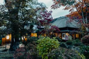 ein Haus mit einem Strohdach in einem Garten in der Unterkunft Kyufukujyuin Takei Ryokan in Nagano