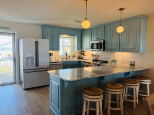 a kitchen with blue cabinets and a white refrigerator at Salty Paradise home in Holden Beach +54 photos