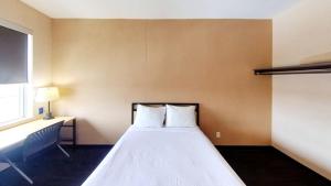 a bedroom with a bed with white sheets and a window at Residence & Conference Centre - Ottawa West in Ottawa