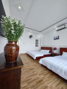 a bedroom with two beds and a vase with flowers on a counter at KHÁCH SẠN PHÚ YÊN - Khách sạn ven biển - trung tâm Tuy Hoà in Tuy Hoa