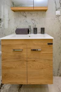 a bathroom with a sink and a wooden cabinet at Sunny Morning at Saint Spyridon by CorfuEscapes in Corfu Town