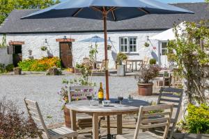 a table with a blue umbrella in a garden at East Trewent Farm in Pembroke