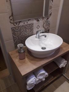 a bathroom with a white sink and towels on a shelf at Konak -Guest house -Ramonda Serbika in Niš