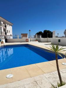 einen Pool mit einer Palme neben einem Gebäude in der Unterkunft Casa Balcones - Benalmadena Pueblo in Benalmádena