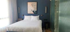 a bedroom with a white bed and a blue wall at SeaNet Hotel By AFI Hotels in Tel Aviv