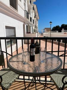 una mesa con 2 botellas y 2 vasos en el balcón en Casa Balcones - Benalmadena Pueblo en Benalmádena