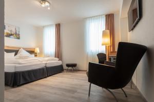a hotel room with a bed and a chair at Hotel in Laisen in Reutlingen