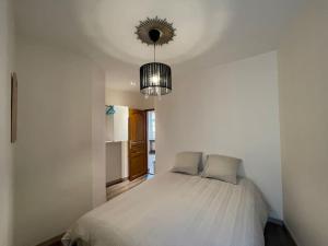 ein Schlafzimmer mit einem weißen Bett und einem Kronleuchter in der Unterkunft Résidence Investar appartement 1 in Montluçon