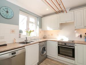 a kitchen with white cabinets and a sink and a clock at 3 West Park Mews in Kingsbridge +16 photos