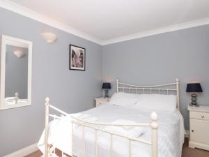 a white bedroom with a white bed and a mirror at 3 West Park Mews in Kingsbridge