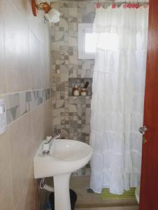 uma casa de banho com um lavatório e uma cortina de chuveiro branca em Petit Valley em Villa Rumipal