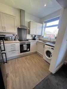 a kitchen with white cabinets and a washer and dryer at Beck View House in Stockton-on-Tees
