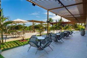 une rangée de tables et de chaises sous une terrasse dans l'établissement Reserva Sauípe - Casa 189, à Costa do Sauipe