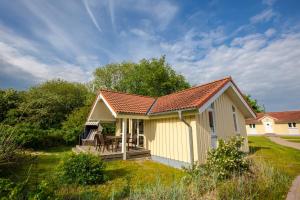 uma pequena casa amarela com um alpendre e um deque em Typ C "Santa Maria" -Fjordhaus- em Pelzerhaken