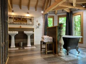 La salle de bains est pourvue de 2 lavabos et d'une baignoire. dans l'établissement Châteaux dans les Arbres, à Clottes