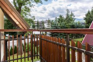 a balcony with a wooden fence and trees at TatryTop Apartamenty Zaciszne in Zakopane