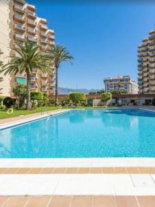 una gran piscina con palmeras y edificios en Apartamento Las Góndolas Playa ALOJAMIENTOS VISTAMAR, en Almuñécar