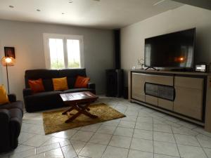 ein Wohnzimmer mit einem Sofa und einem Flachbild-TV in der Unterkunft La Rosée Dar - Villa avec piscine in Martin-Église