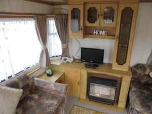 a living room with a tv and a fireplace in a caravan at 5 Berth on Coral Beach (Granada) in Ingoldmells