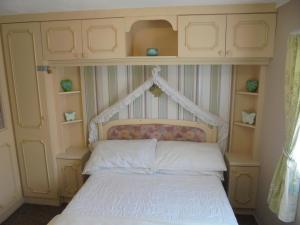 a bedroom with a bed with a headboard and shelves at 5 Berth on Coral Beach (Granada) in Ingoldmells