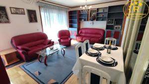 a living room with a table and red chairs at Fractal Residence Apartman Vrnjačka Banja in Vrnjačka Banja