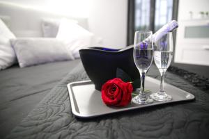 ein Tablett mit zwei Weingläsern und einer Rose auf dem Bett in der Unterkunft The Marble House in Bari