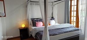 a bedroom with a canopy bed with pink pillows at Mount Elegance in Nuwara Eliya