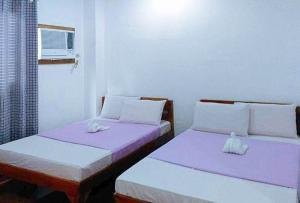 duas camas num quarto com roxo e branco em RedDoorz @ Reana Seaside Pensione House Guindulman em Guindulman