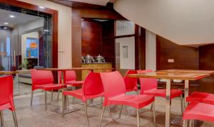 a dining room with red chairs and tables at Treebo Trend Azure in Varanasi