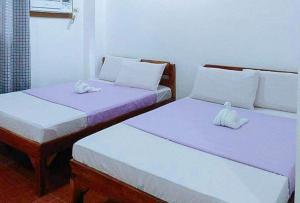 duas camas sentadas uma ao lado da outra num quarto em RedDoorz @ Reana Seaside Pensione House Guindulman em Guindulman